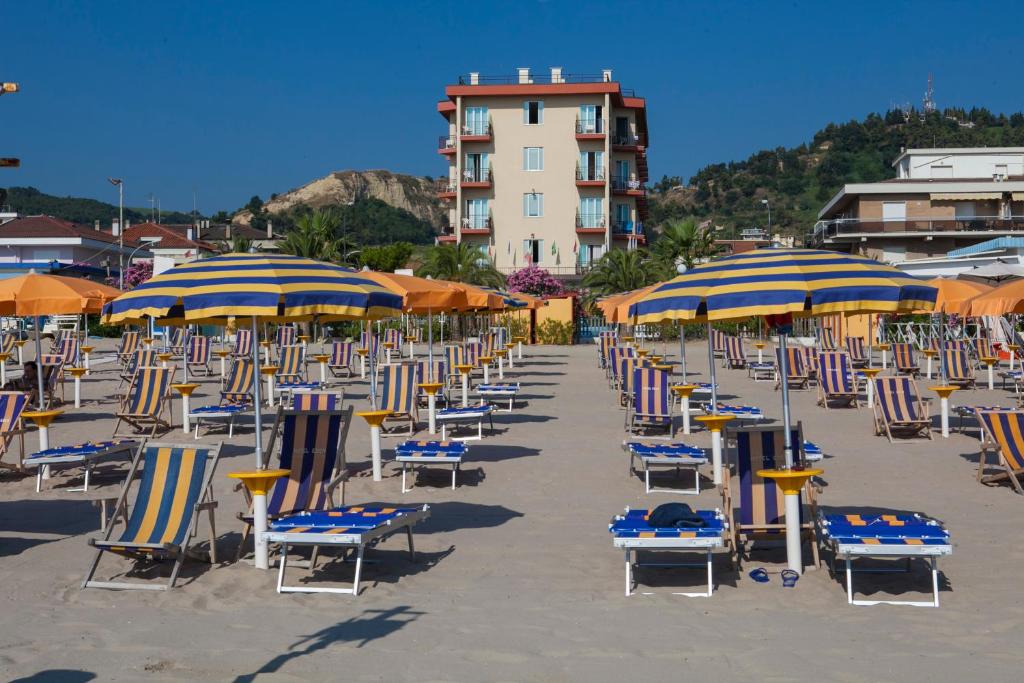 un mucchio di sedie e ombrelloni su una spiaggia di Hotel Eden a Grottammare