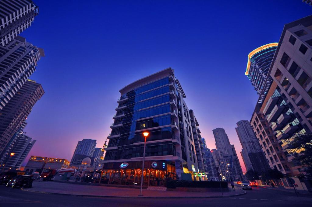 um edifício de vidro alto em uma cidade à noite em Jannah Place Dubai Marina no Dubai