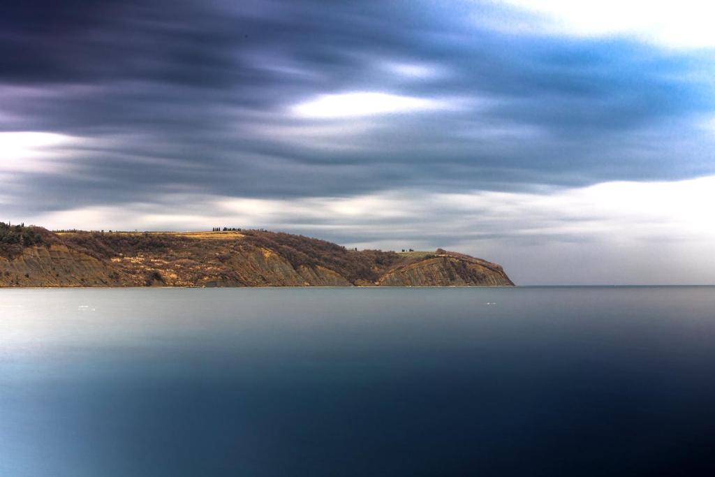 a large body of water with a hill in the background at Hotel Cliff Belvedere in Izola