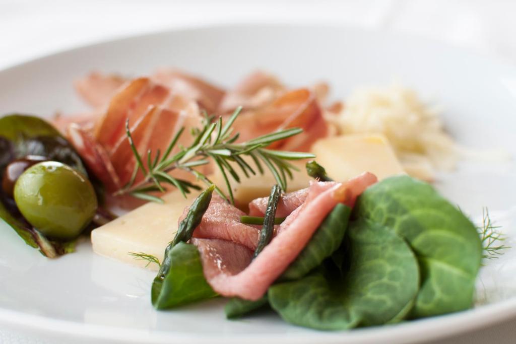 a plate of food with meat and cheese and vegetables at Hotel Cliff Belvedere in Izola
