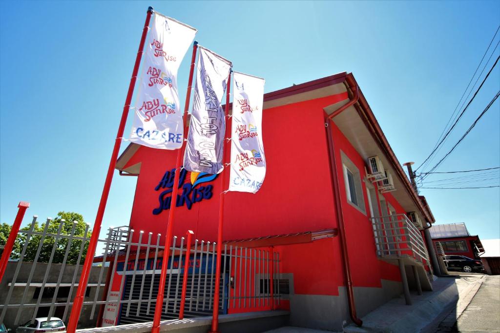 a red building with two flags in front of it at Aby sunrise in Orşova