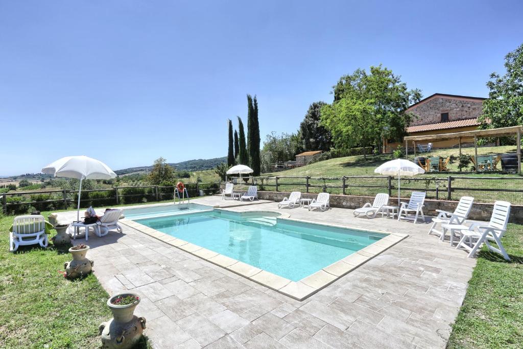 a swimming pool with chairs and umbrellas in a yard at Agriturismo Cappellese in Castelnuovo della Misericordia