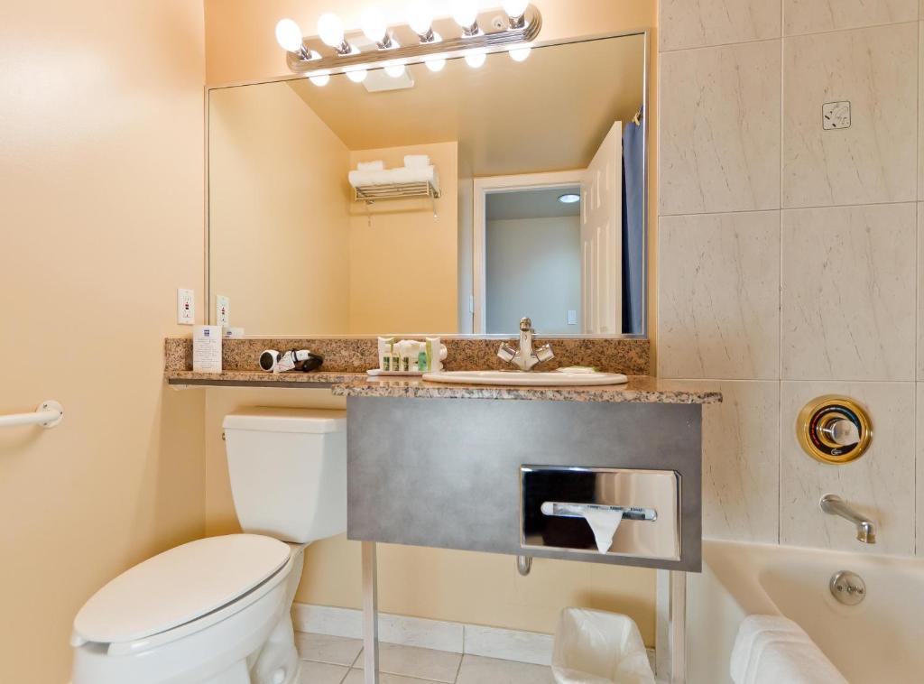 a bathroom with a toilet and a sink and a mirror at Rosedale on Robson Suite Hotel in Vancouver