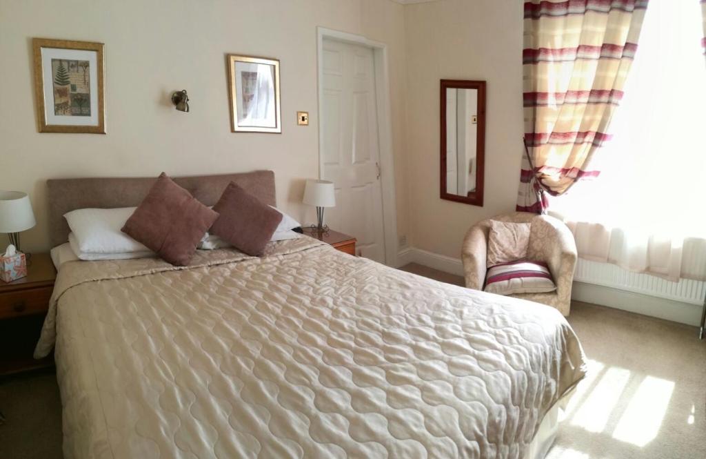 a bedroom with a large bed and a chair at The Aidan Guest House in Stratford-upon-Avon