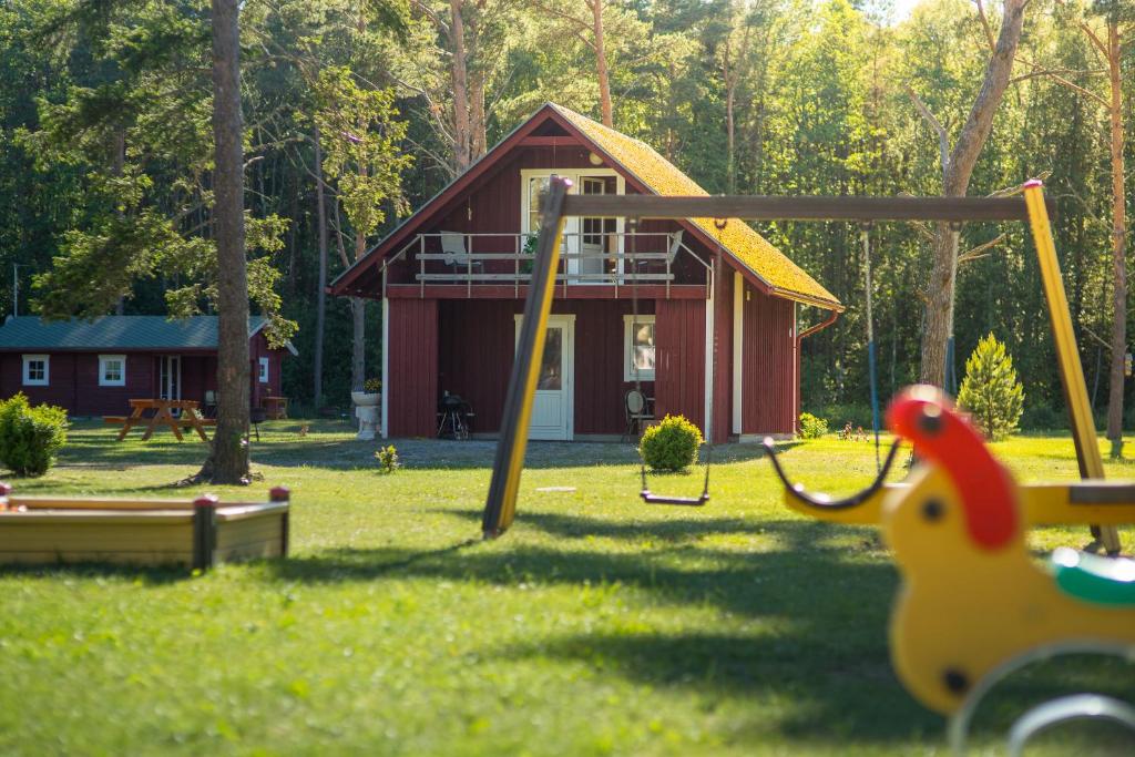 un parque infantil frente a una pequeña cabaña roja en Tehumardi Camping en Salme