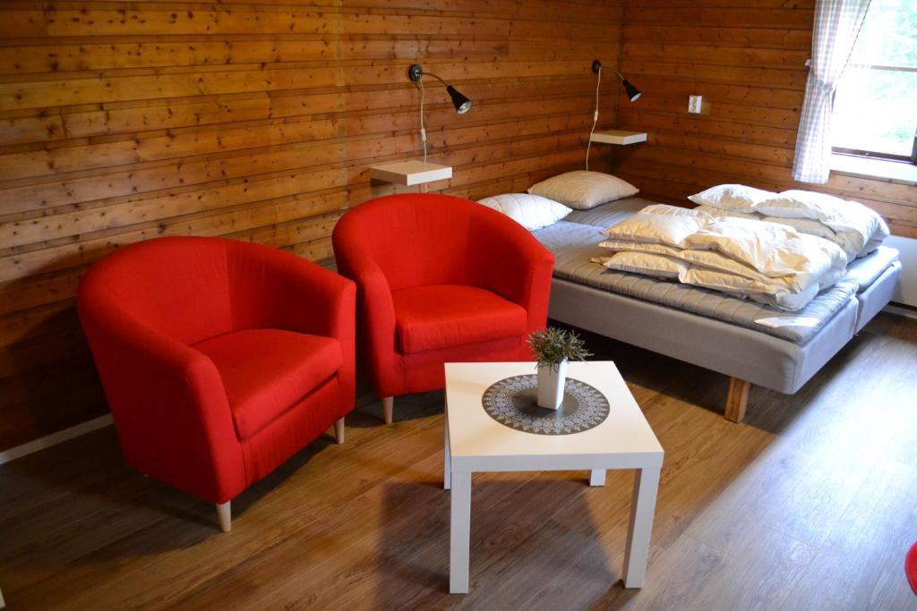 - une chambre avec deux chaises rouges, un lit et une table dans l'établissement Doro Camp Lapland, à Dorotea
