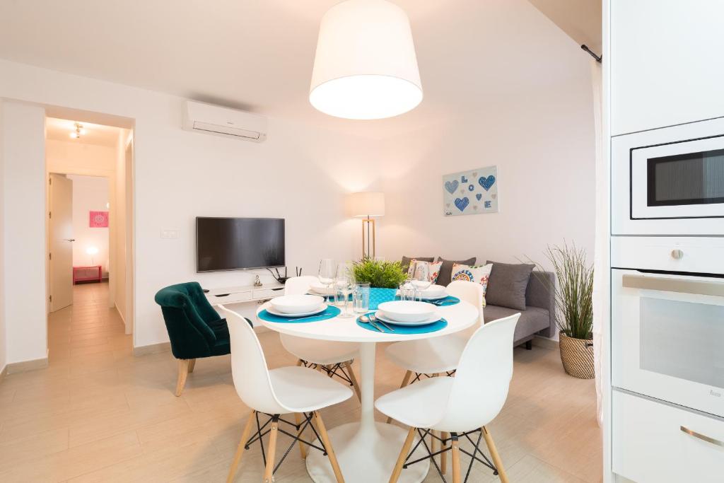 een eetkamer en een woonkamer met een witte tafel en stoelen bij Peña City Center Apartment in Málaga