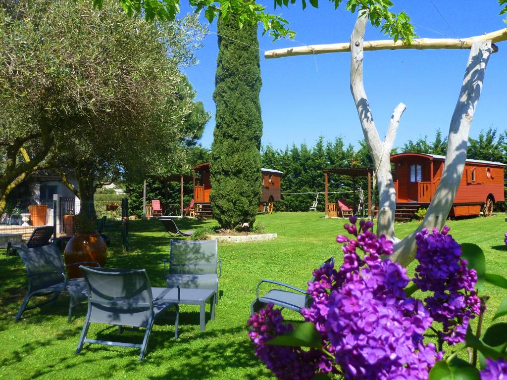 un grupo de sillas y flores en un patio en Gites et Roulottes Du Grand Puits, en Saint-Laurent-dʼAigouze