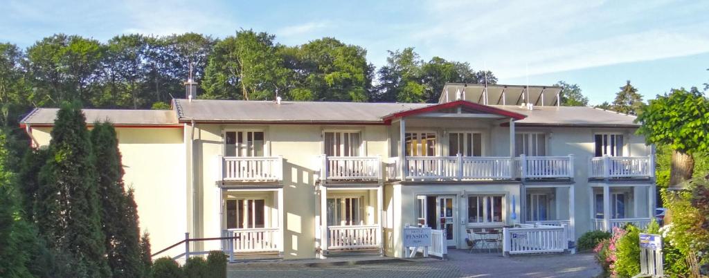 un gran edificio blanco con balcones y árboles en Hotel Pension Bellevue, en Bad Doberan