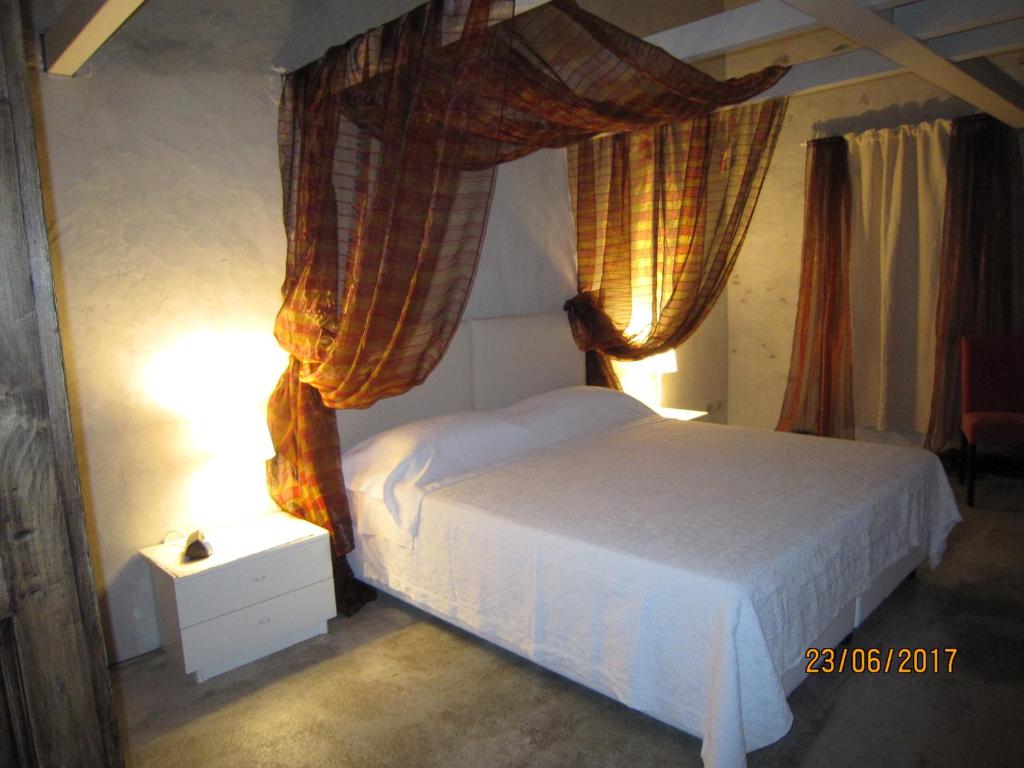クーネオにあるCasa Torre Alleraのベッドルーム1室(白いベッド1台、カーテン、ランプ付)