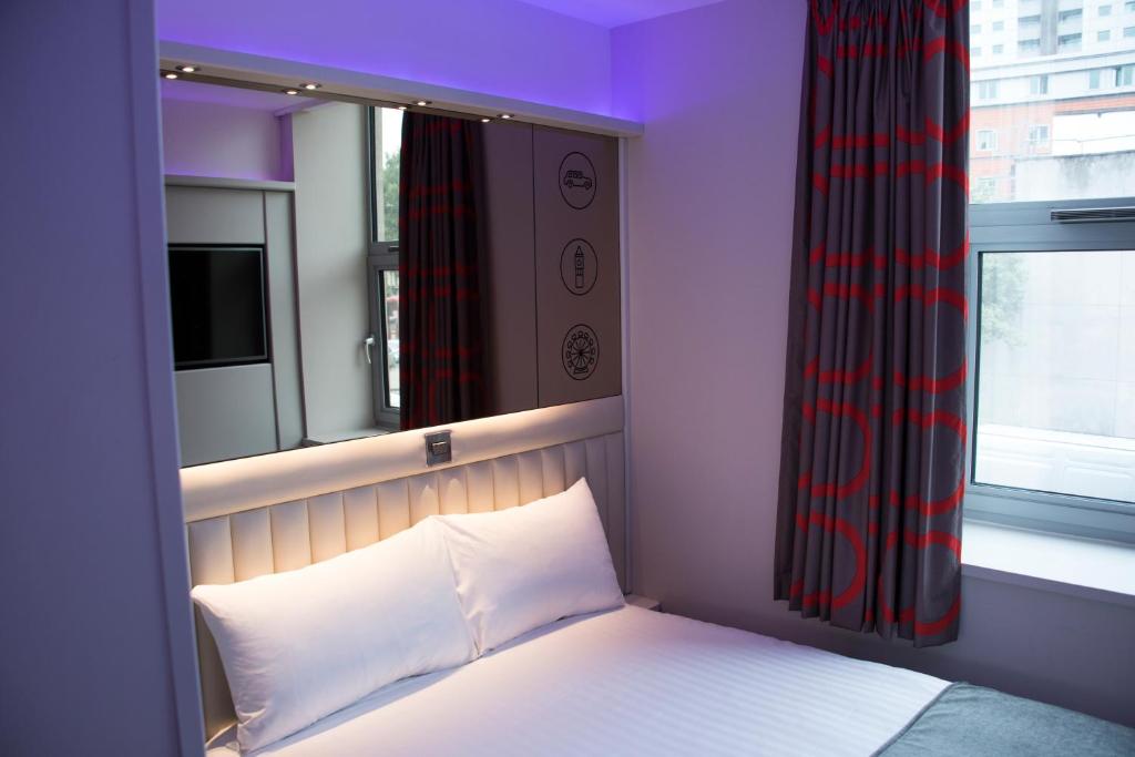 um quarto com uma cama com uma janela e uma cama branca sidx sidx em Point A Hotel London Westminster em Londres