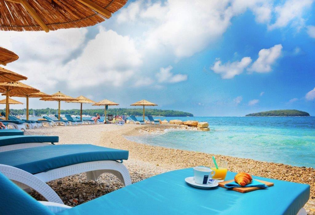 uma mesa azul e cadeiras numa praia com o oceano em Apartman Desi em Funtana