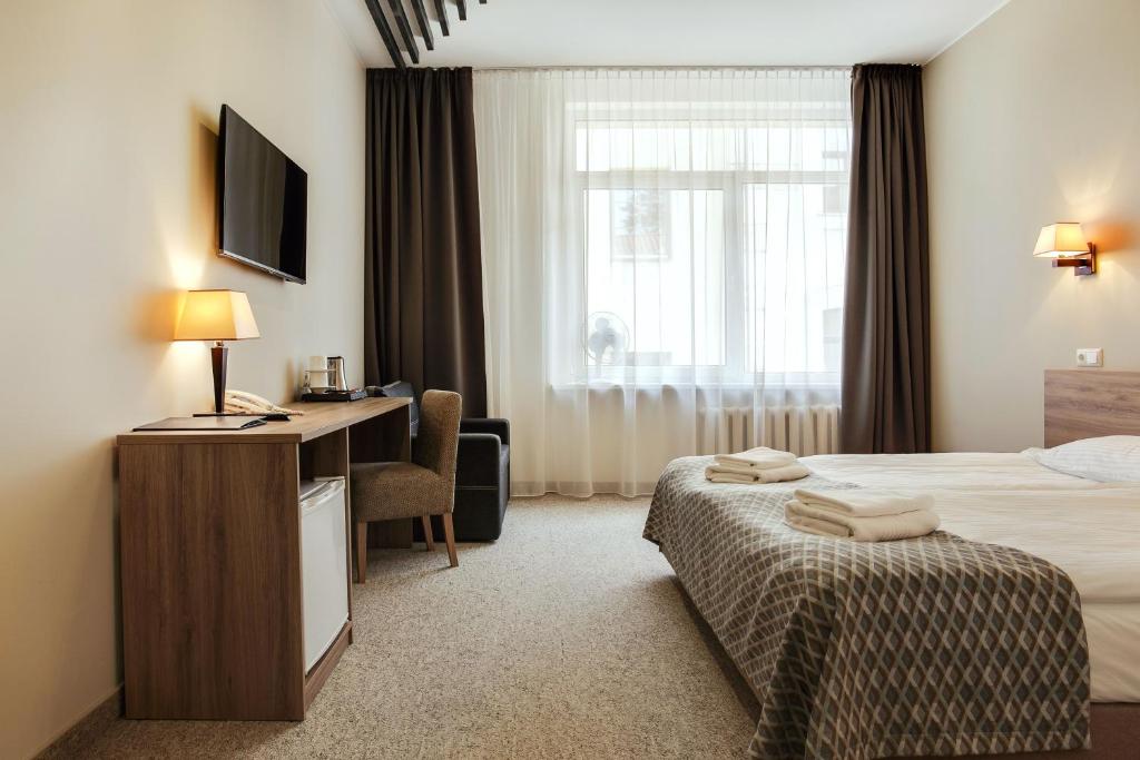 um quarto de hotel com uma cama, uma secretária e uma janela em Old Town Trio em Vilnius