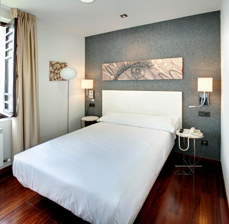 1 dormitorio con 1 cama blanca grande y 2 lámparas en Hotel Lastres Miramar, en Lastres
