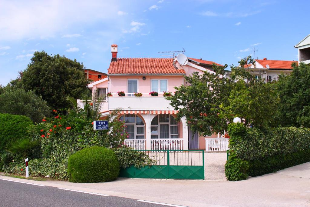una casa rosa con una valla delante en Apartments Tonka, en Primošten