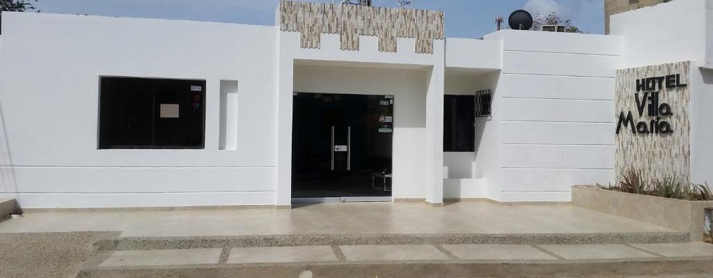 a building with white walls and a black door at Hotel Villa Maria Uribia in Uribia