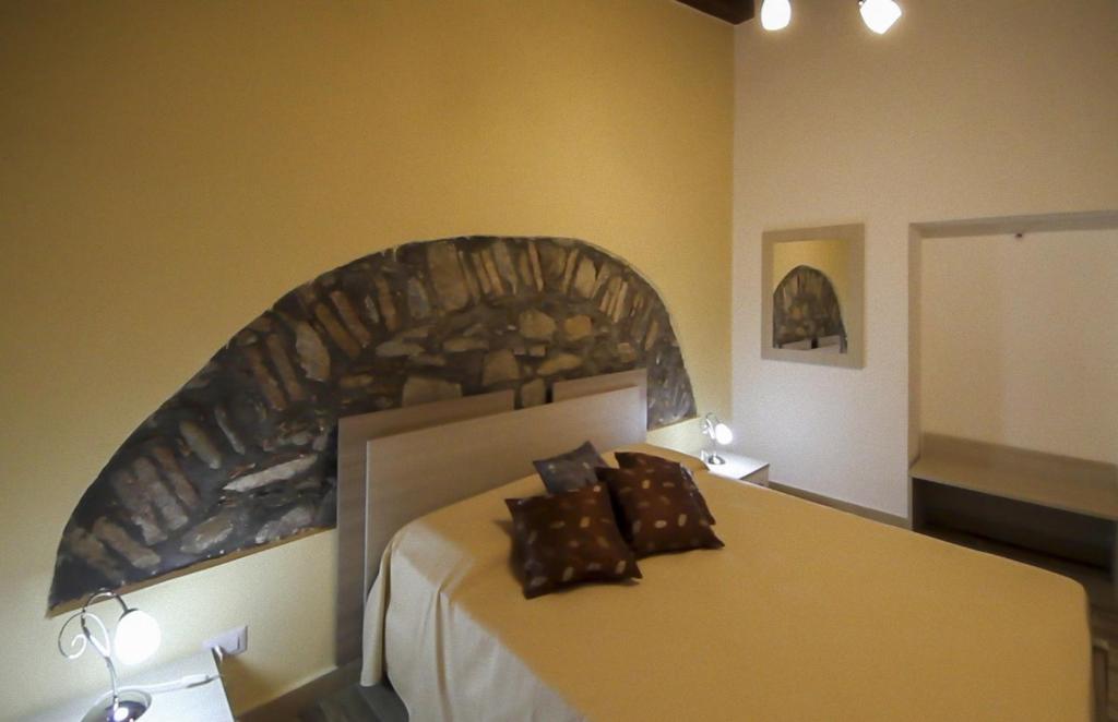 1 dormitorio con 1 cama grande y cabecero de piedra en Casa Vacanze Camastra, en Santo Stefano di Camastra