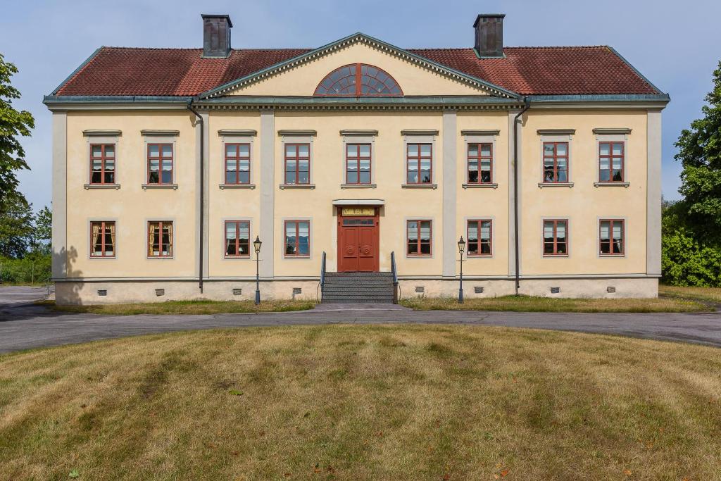 ein großes Gebäude mit einer roten Tür auf einem Feld in der Unterkunft Storebro Herrgård in Vimmerby