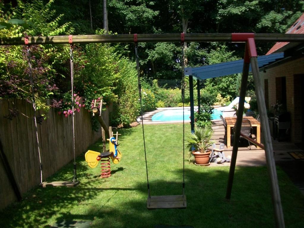 a swing in a yard next to a pool at La Maison D'hôtes Du Mont Des Cats in Godewaersvelde