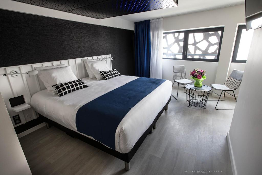 una camera da letto con un grande letto e tavoli e sedie di Hôtel La Fabrique a La Rochelle