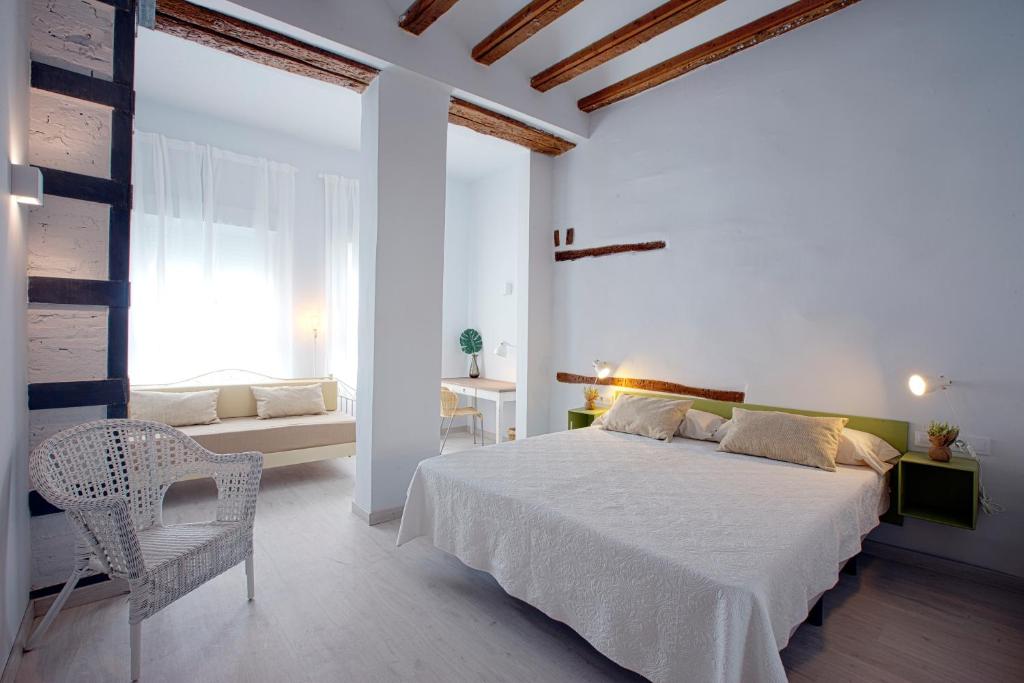 um quarto branco com uma cama e uma cadeira em OttoH Charm Stay em Valência