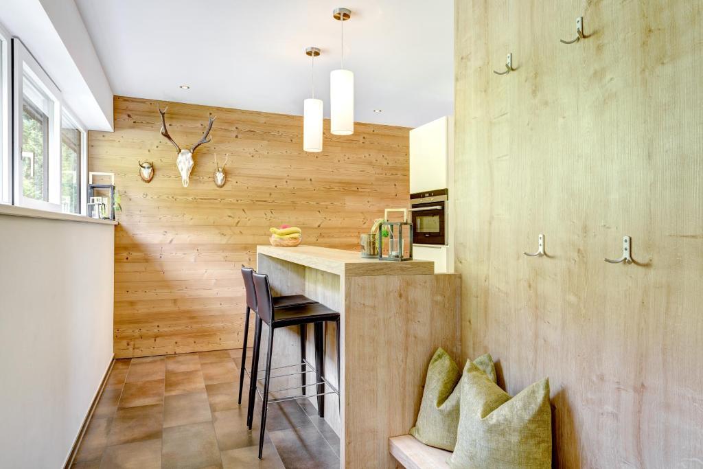 cocina con paredes de madera y barra con sillas en Bergzauber Appartements, en Brand