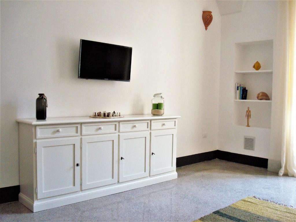 Armario blanco con TV de pantalla plana en la pared en A casa di Vivì, en Martano