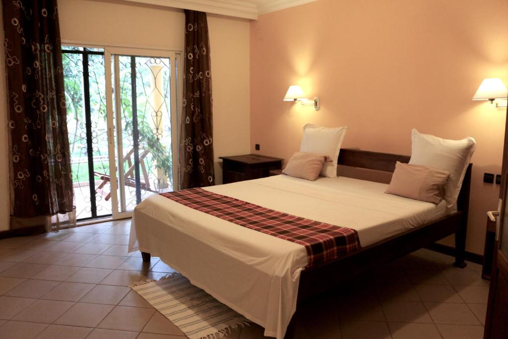 um quarto com uma cama e uma grande janela em AR Sun Hotel em Antsiranana