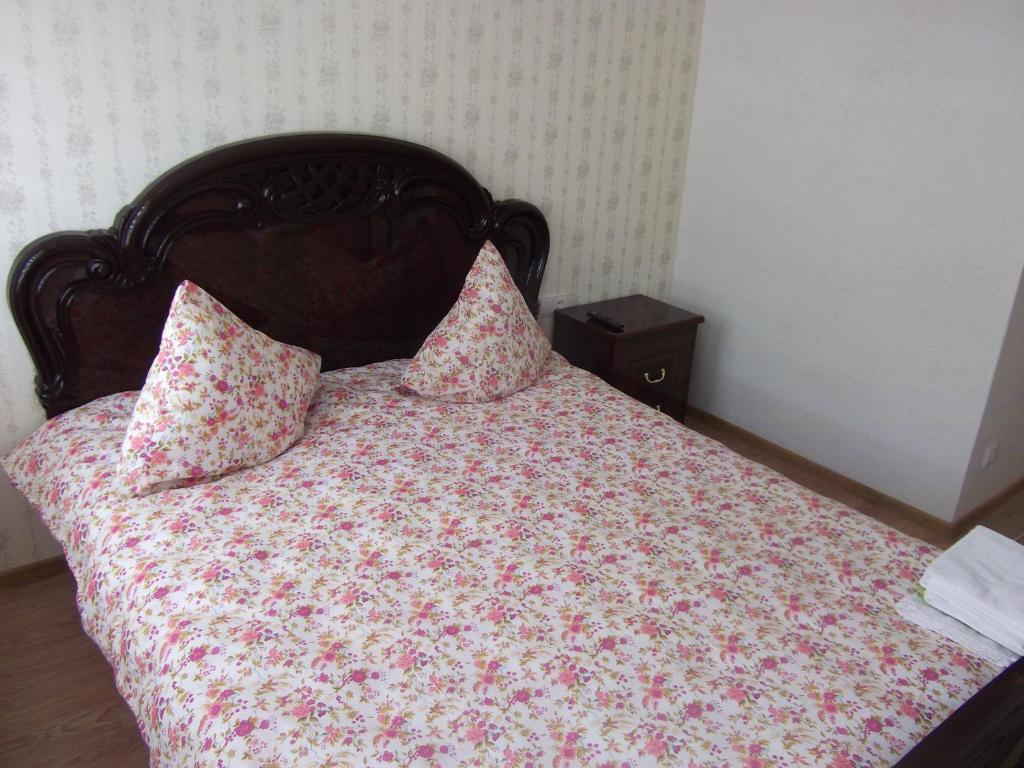 a bed with a floral comforter and two pillows at Deima in Nida