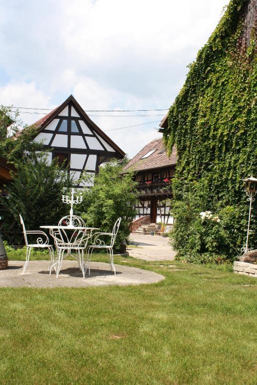 uma mesa e cadeiras em frente a um edifício em La Grange aux Coqs em Ittenheim