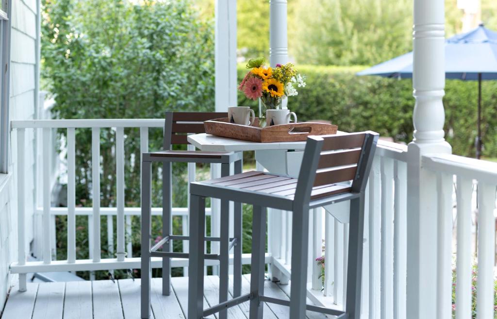 einen Tisch und zwei Stühle auf einer Veranda mit Blumen in der Unterkunft West Neck Guesthouse in Shelter Island Heights