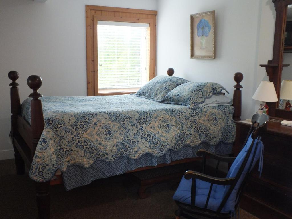 a bedroom with a bed with a quilt and a window at Scarborough Inn in Manteo