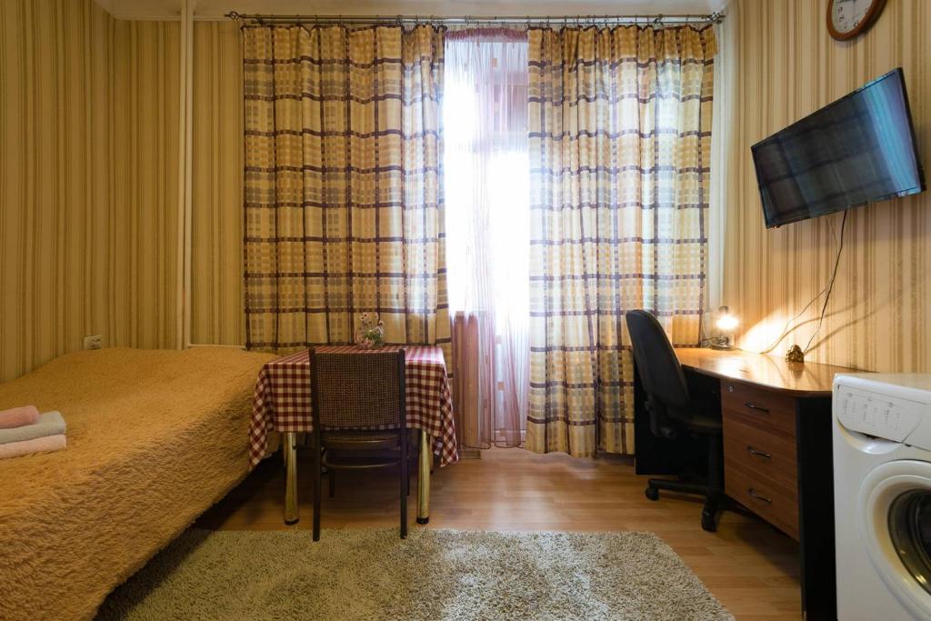 a bedroom with a bed and a table and a window at Apartment Nadezhda at Kabanbay Batyr 122 in Almaty