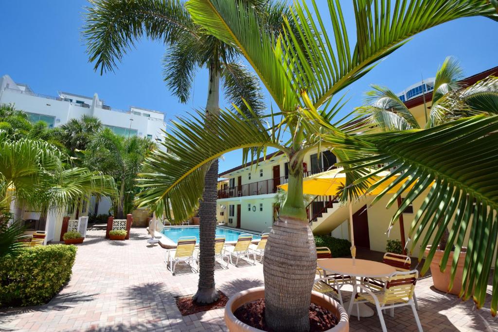 un patio con mesas, palmeras y una piscina en Surf Side Resort, en Pompano Beach
