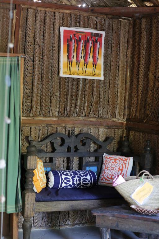 a wooden bench with pillows and a picture on the wall at The Beach Crab Resort in Pangani