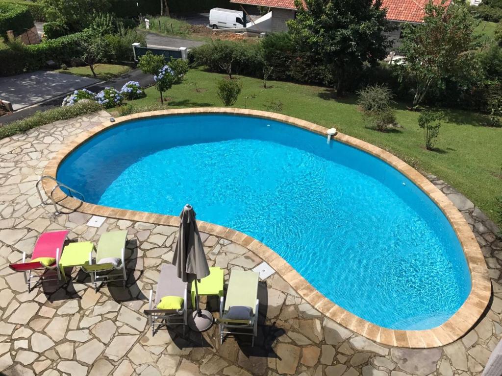 una imagen de una piscina con sillas y sombrilla en Guest house Maison Iratzean, en Ascain