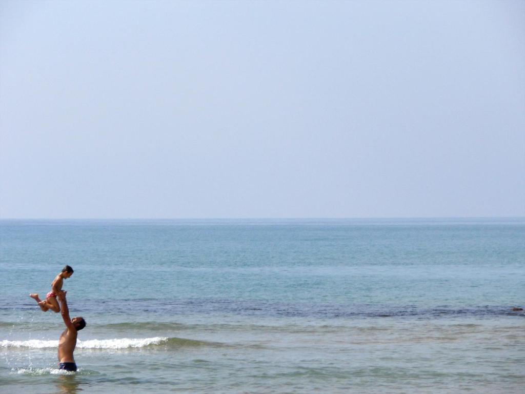 Ein Mann und ein Kind spielen im Wasser am Strand in der Unterkunft Corsaro B&B in Donnalucata