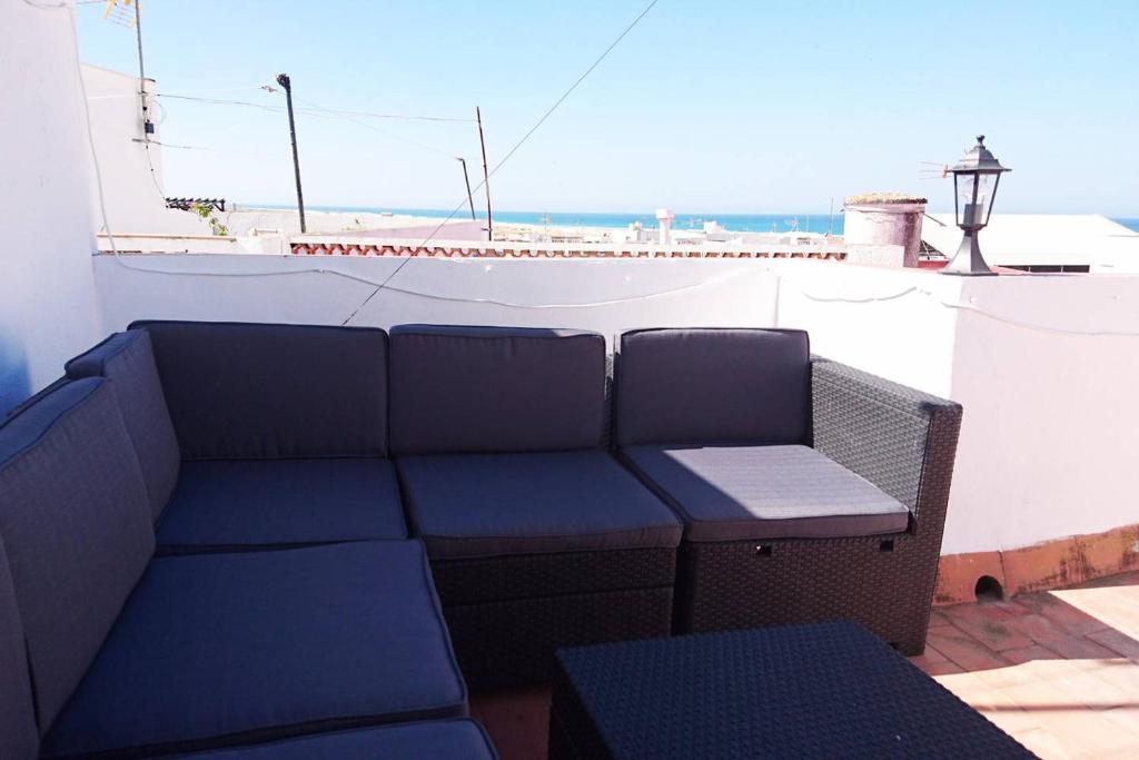 a bench and table on a balcony with a view of the ocean at Casa Conil Cruz in Conil de la Frontera