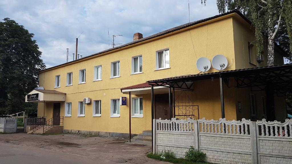 un edificio amarillo con satélites encima en Glamour Hotel en Luhyny