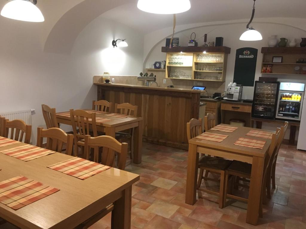 um restaurante com mesas e cadeiras de madeira e um balcão em Penzion Bednářův dvůr em Bohušice