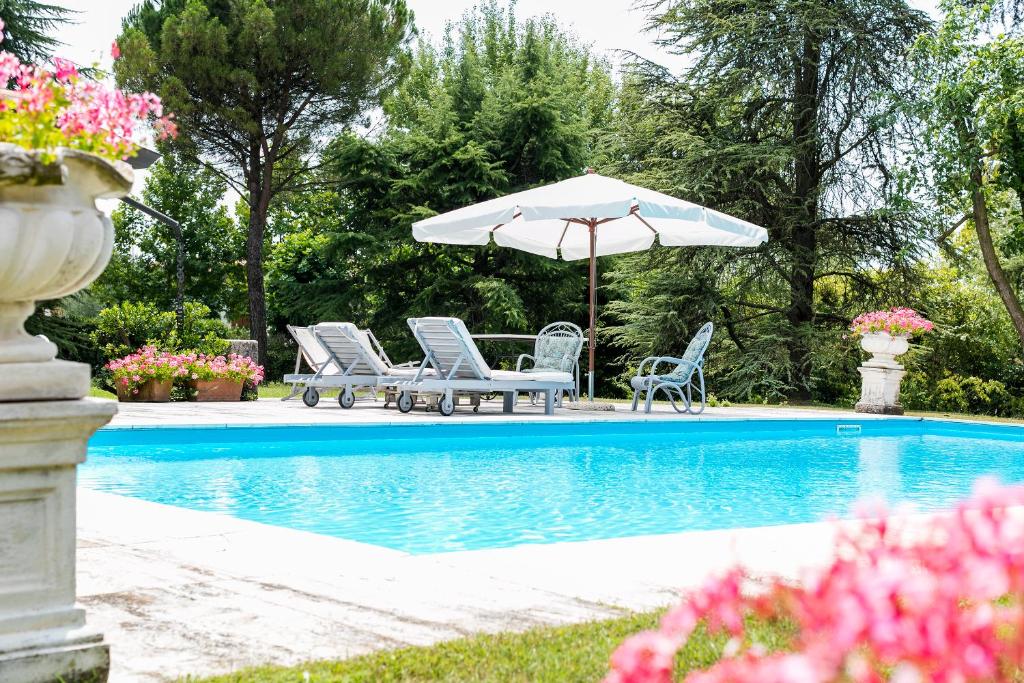 een groep stoelen en een parasol naast een zwembad bij Le Margherite in Manerba del Garda