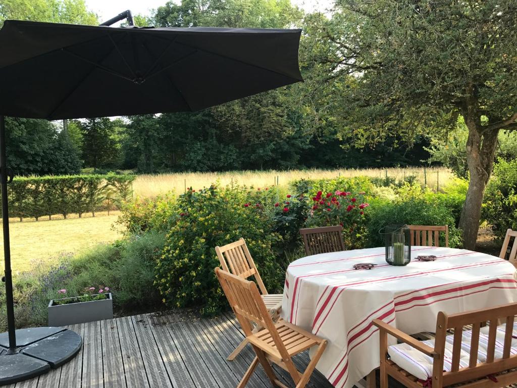 einen Tisch und Stühle mit einem Sonnenschirm auf einer Terrasse in der Unterkunft Belle Dépendance du Château le Parc avec sa piscine in Ardentes