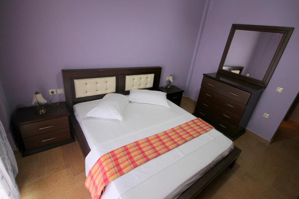 a bedroom with a large bed and a mirror at Mihal Suites in Sarandë