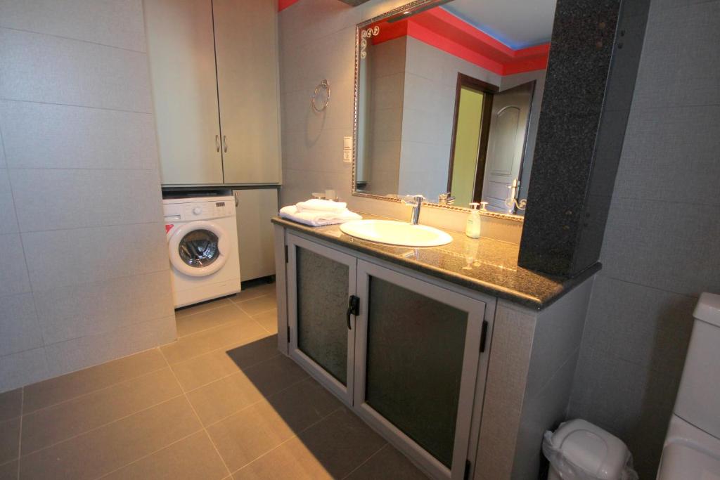 a bathroom with a sink and a washing machine at Mihal Suites in Sarandë