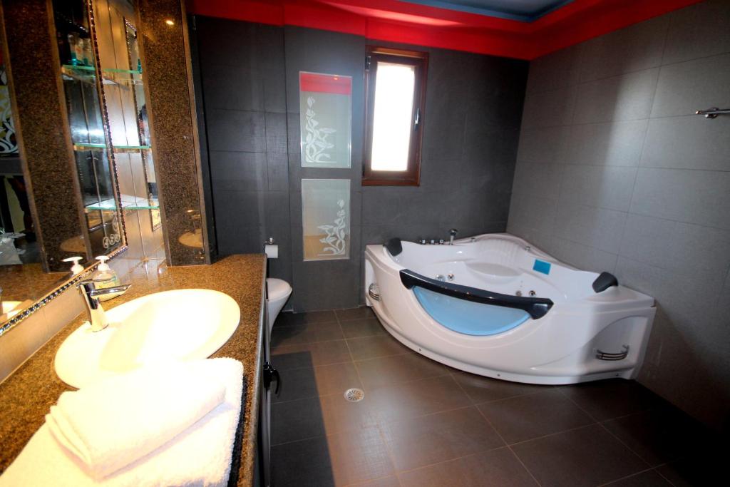 a bathroom with a tub and a sink and a toilet at Mihal Suites in Sarandë