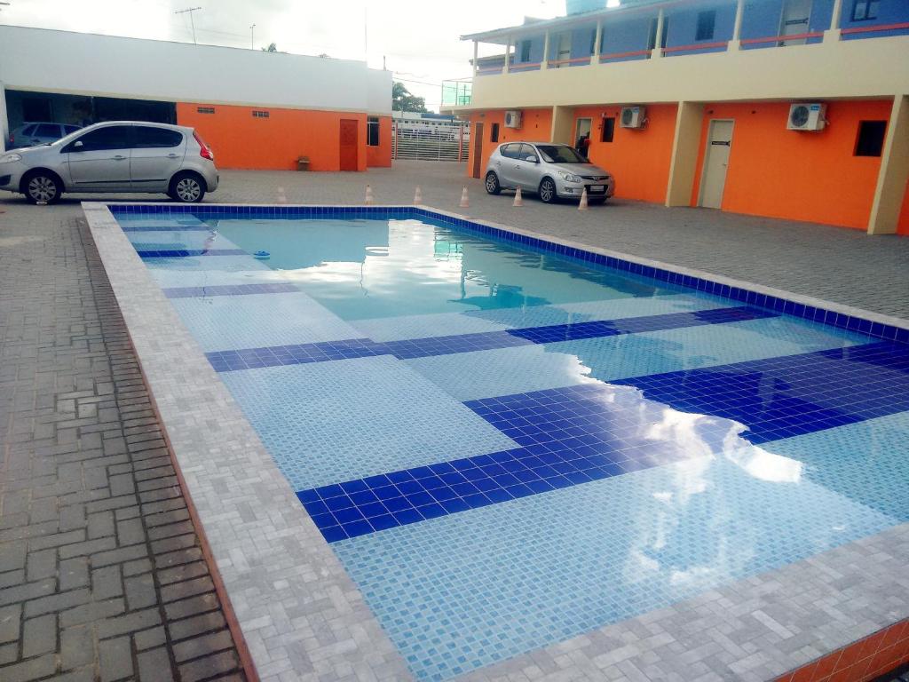 a swimming pool with blue tiles in a parking lot at Pousada Itararé in Campina Grande