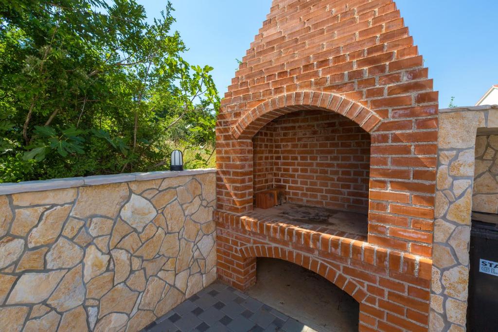 an outdoor brick oven with a stone wall at Cool Šilo Appartement Resort in Šilo