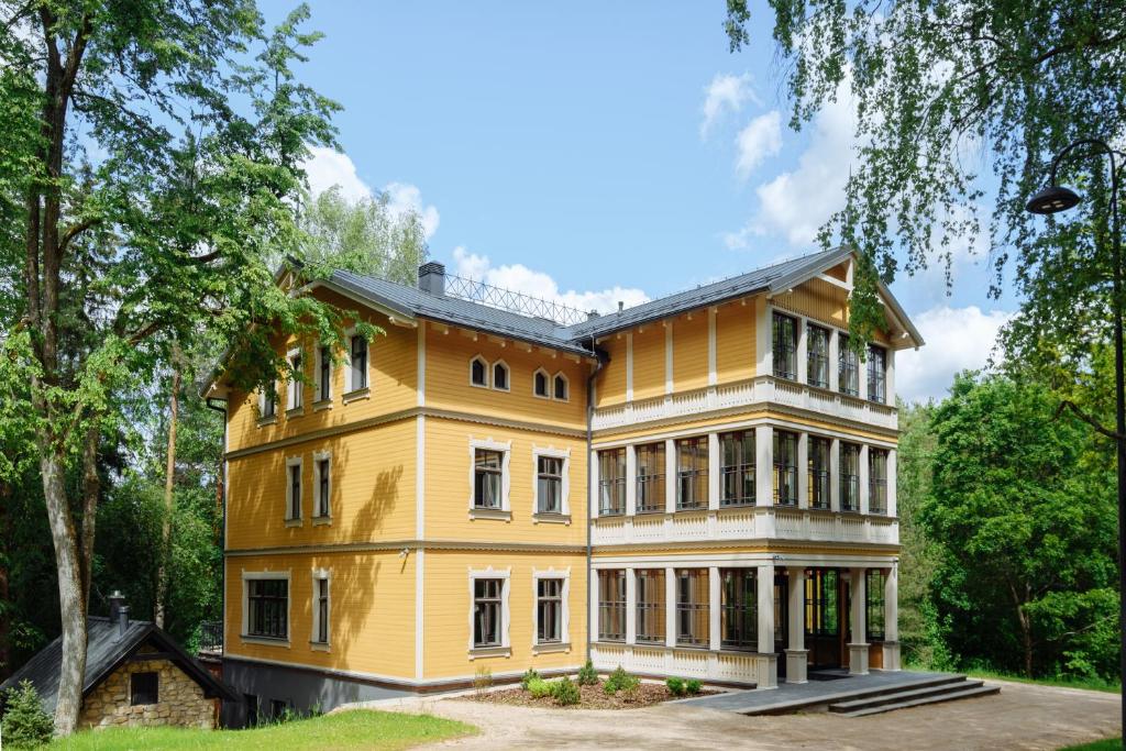 a large yellow house with trees in front of it at Villa Santa in Cēsis