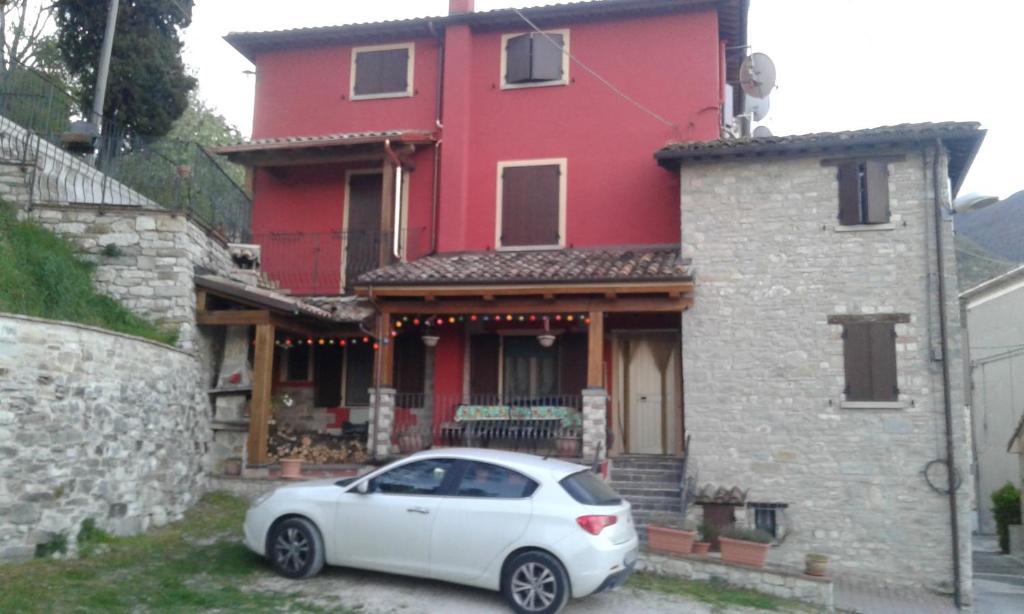 un coche blanco estacionado frente a una casa roja en Il Piccolo Granaio, en Scavolino