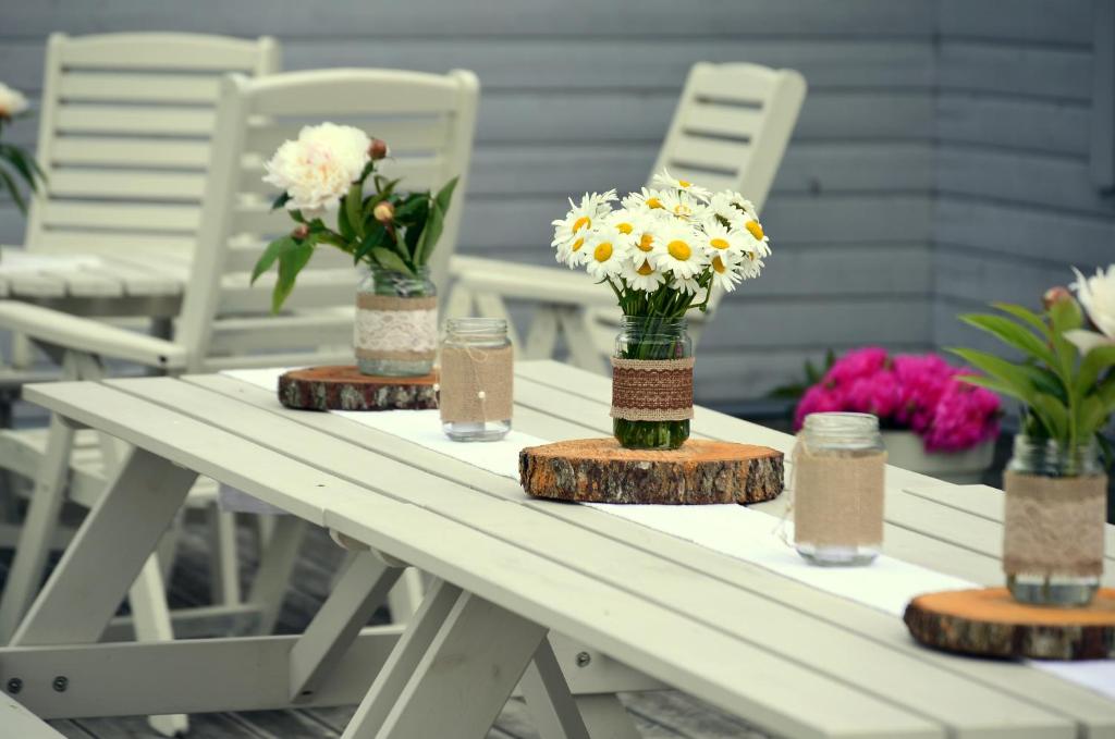 una mesa de picnic blanca con flores en jarrones en Vinni Hostel, en Vinni